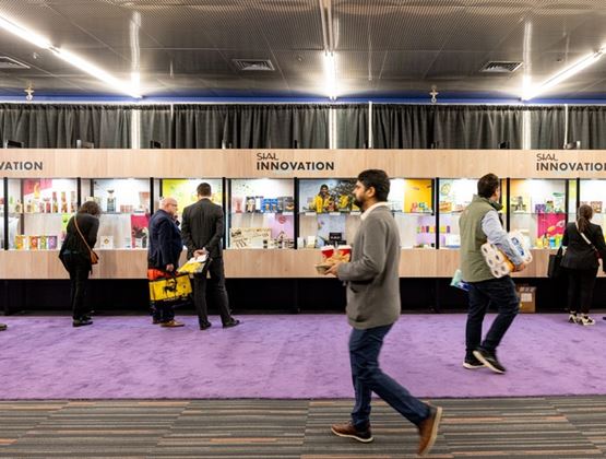 Visitors walking past the innovation area of a trade show showcasing food products.