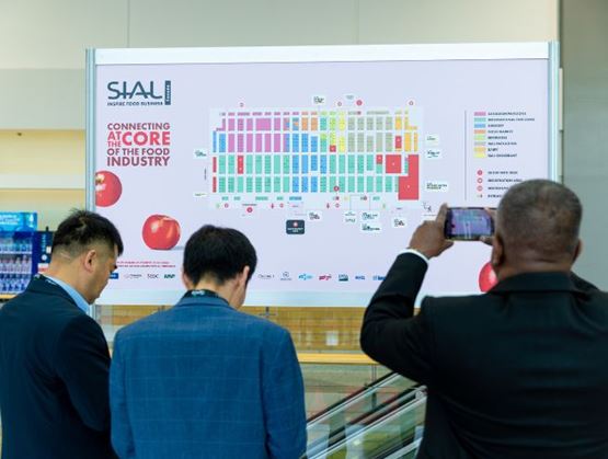 People taking a picture and looking at SIAL Canada hall plan