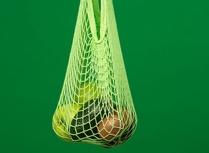 Fruit in a bag with a hand and green background