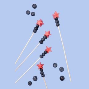 Skewers made of blueberries and watermelon stars on a light blue background.