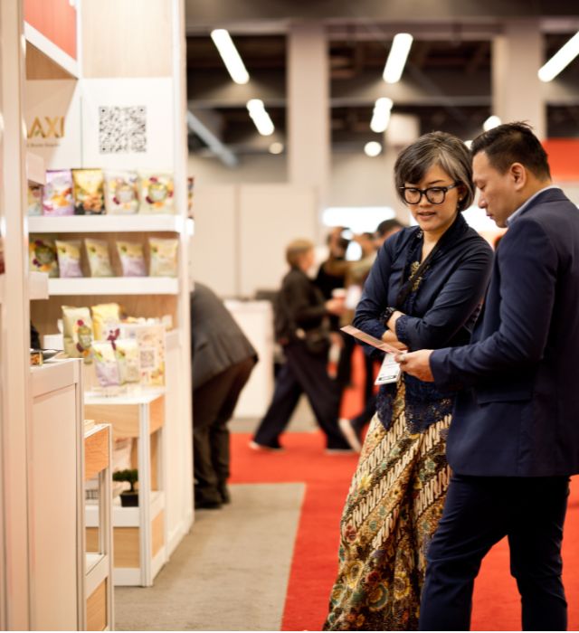 Discussion between buyer and exhibitor at a food products booth during an international trade show