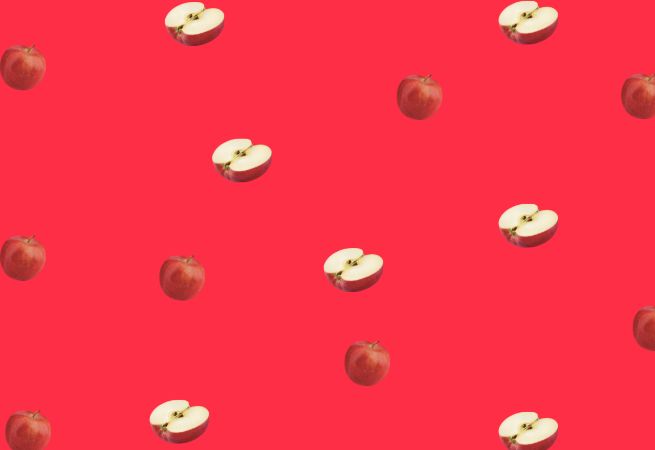 Repeating pattern of whole and sliced apples on a bright red background illustrating a vibrant fruit theme