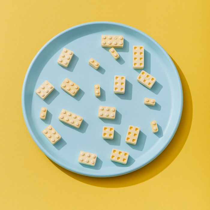 Innovative brick-shaped food pieces arranged on a blue plate against a yellow background