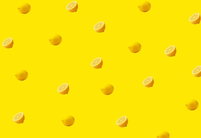 Pattern of whole and sliced lemons on a yellow background illustrating fresh and natural food