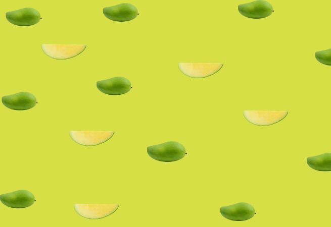 Pattern of whole and sliced mangoes on a green background illustrating fresh and tropical food