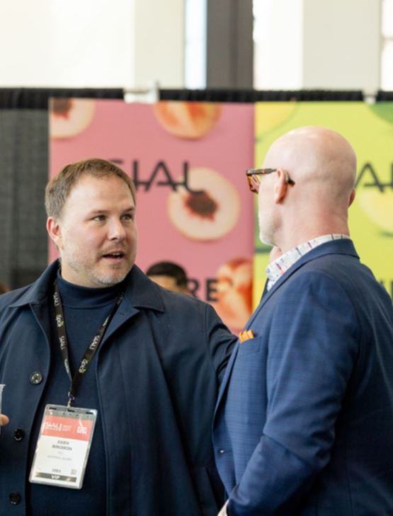 Professionals talking at a colorful booth during an international food trade show