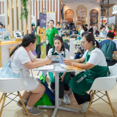Business meeting between participants seated at a table during a busy food industry trade fair.