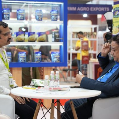 Business discussion between two men seated at a table at an agro export exhibition booth.