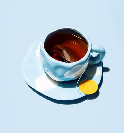 Blue cloud-pattern cup with tea and teabag on pastel blue background