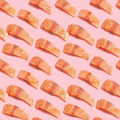 Salmon slices arranged in a repetitive pattern on a pink background.