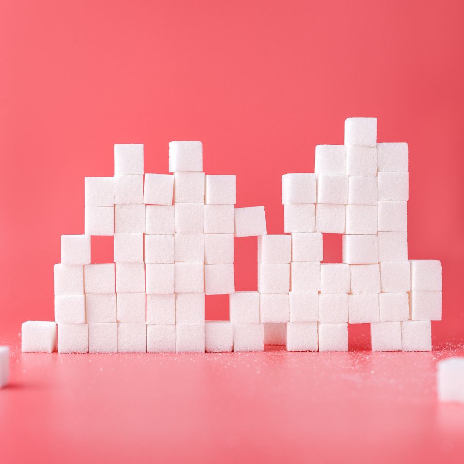 White sugar cubes stacked in a graphic structure on a pink background.